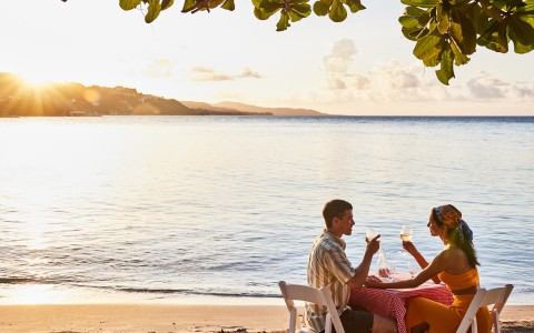 a man and woman sitting at a table on a beach