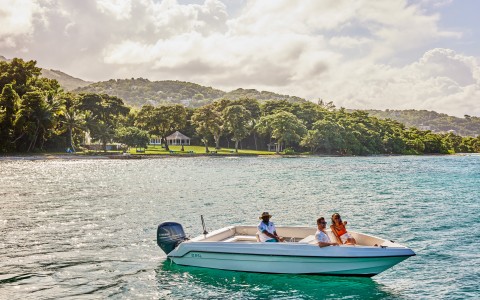 a group of people in a boat on water with trees in the background