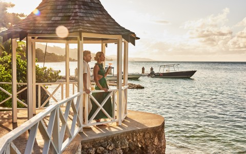 a man and woman standing on a porch overlooking a body of water