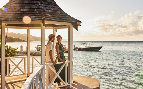 a man and woman standing on a porch by water