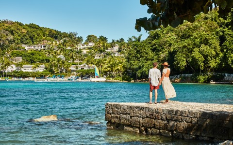 a man and woman standing on a stone wall overlooking a body of water