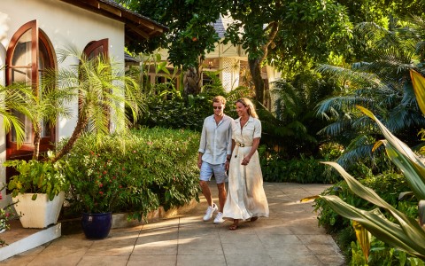 a man and woman walking on a path with plants and trees