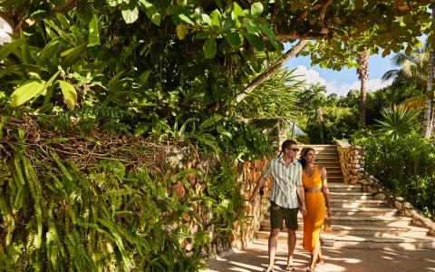 a man and woman walking down a path with stairs and trees