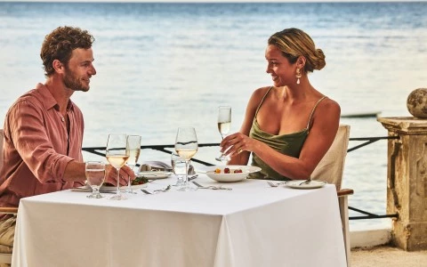 a man and woman sitting at a table with food and drinks