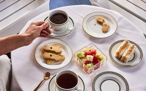 a person holding a cup of tea and a plate of food