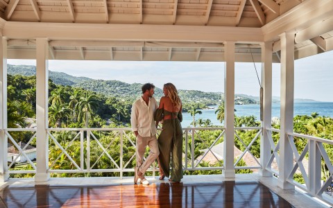 a man and woman standing on a porch looking at each other