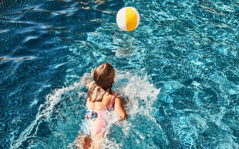 a girl in a pool with a ball
