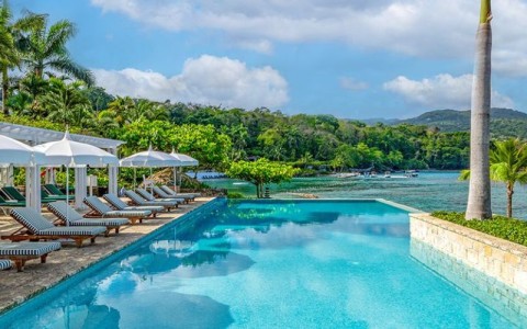 a pool with chairs and umbrellas by a body of water