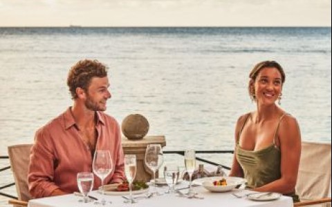 a man and woman sitting at a table with food and drinks