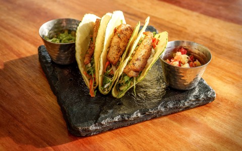 a group of fish tacos on a slate plate