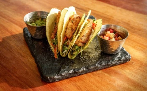 a group of fish tacos on a slate plate