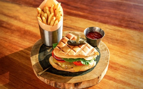 a sandwich and fries on a wood plate