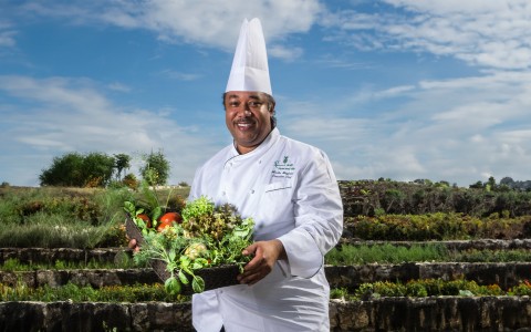 a man in a chef's hat holding a basket of vegetables