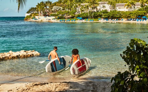 a man and woman carrying surfboards in water
