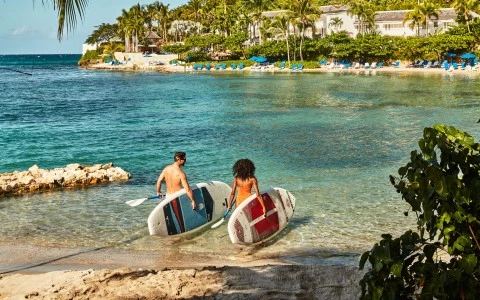 a man and woman carrying surfboards in water