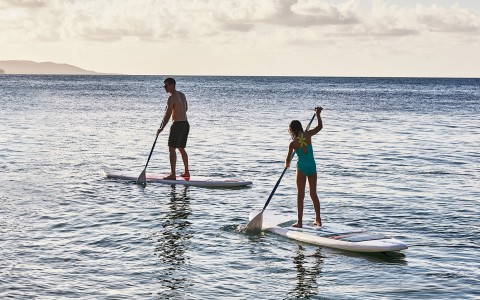 a man and woman on paddle boards in the water