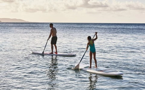 a man and woman on paddle boards in the water