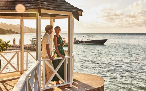 a man and woman standing on a gazebo by the water