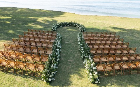a group of chairs lined up on grass with flowers