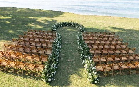 a group of chairs lined up on grass with flowers