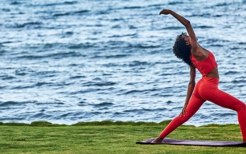 a woman stretching on a mat near water