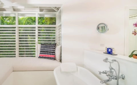 a white bathroom with a window and a bathtub