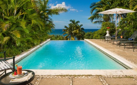 a pool with a deck and chairs and trees
