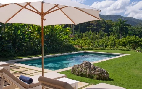 a pool with a white umbrella and chairs