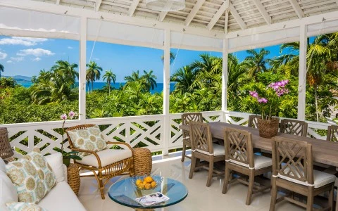 a patio with a table and chairs and a table with a view of the ocean