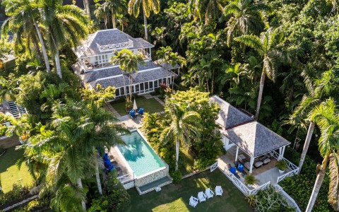 a house with a pool surrounded by palm trees