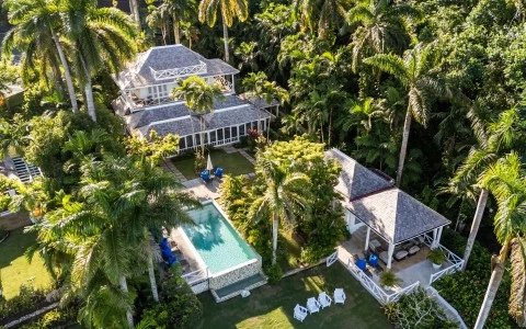a house with a pool surrounded by palm trees