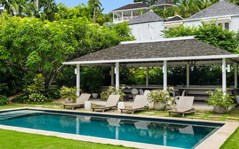 a pool with chairs and a gazebo in the middle of a yard