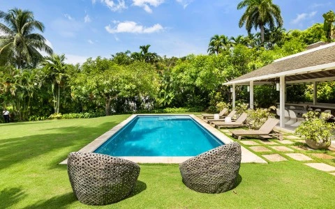 a pool with chairs and a gazebo in the background