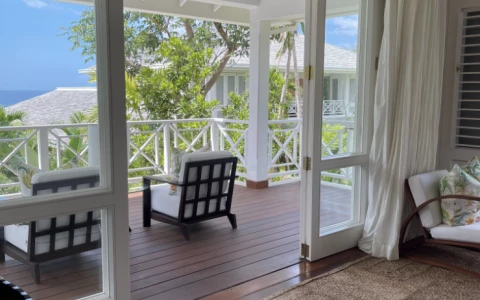 a room with a deck and a patio with a view of the ocean