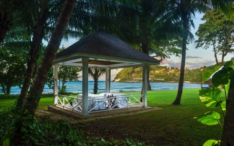 a gazebo with a table and a body of water in the background