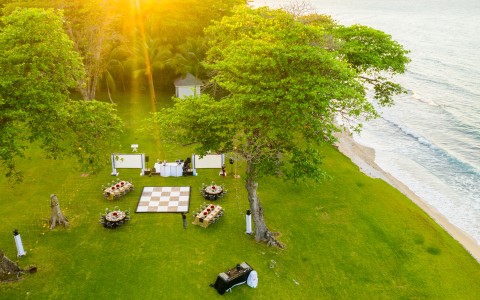 a group of tables and chairs on a lawn by a body of water