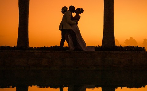 a silhouette of a man and woman kissing by a body of water