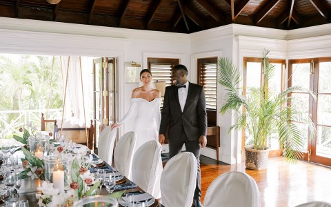 a man and woman standing next to a table with a table set with flowers