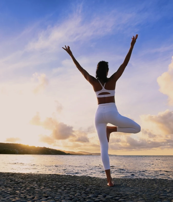 a woman standing on one leg with arms raised in the air
