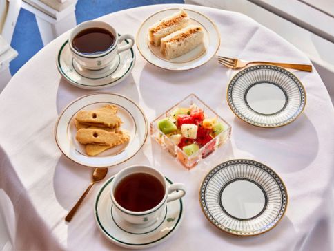a table with plates and cups of tea and fruit