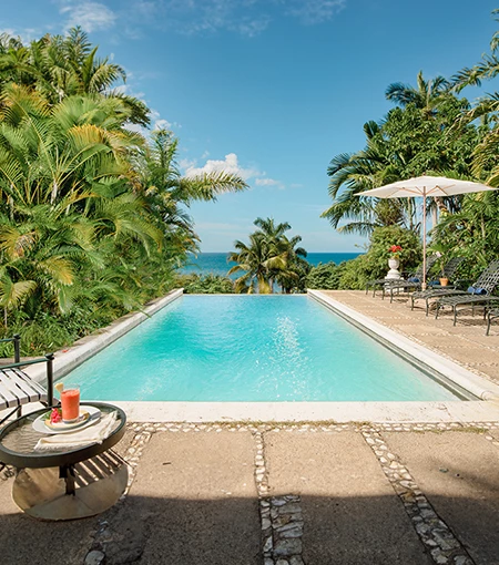 a pool with chairs and umbrellas by the ocean