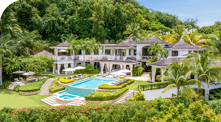a large white house with a pool surrounded by trees