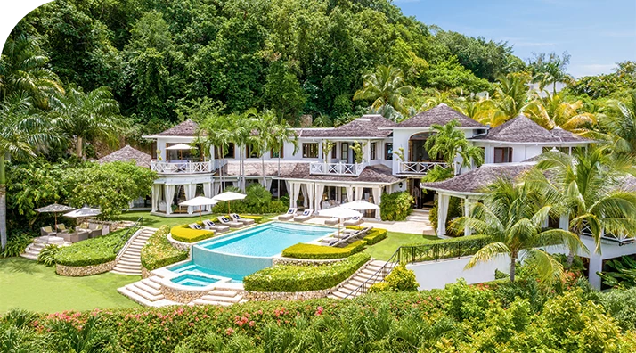 a large white house with a pool surrounded by trees