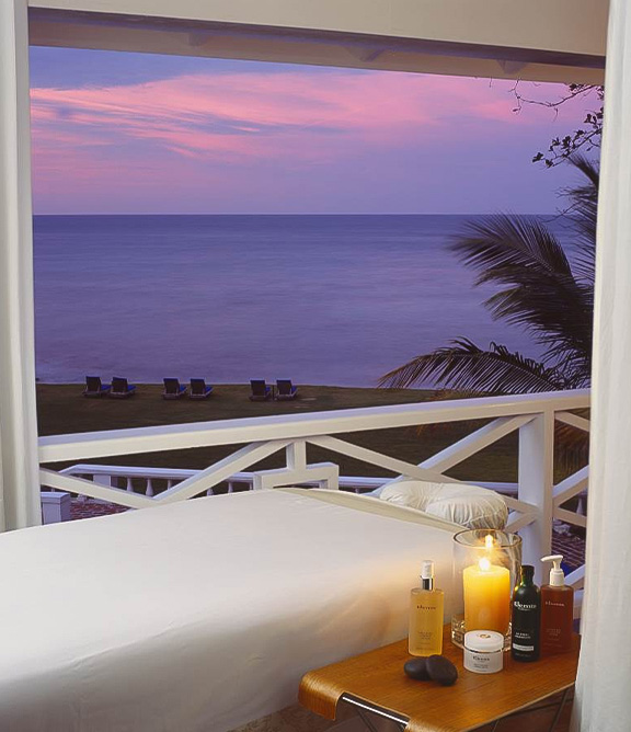 a massage table with candles and candles on a balcony overlooking the ocean