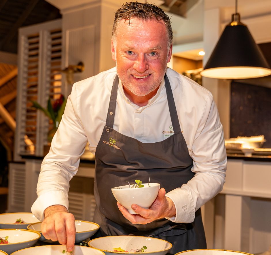 a man in an apron holding a bowl of food