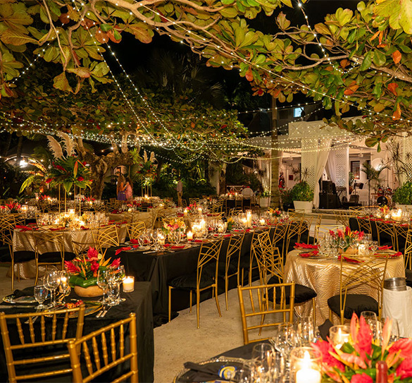 a group of tables with candles and flowers under a string of lights