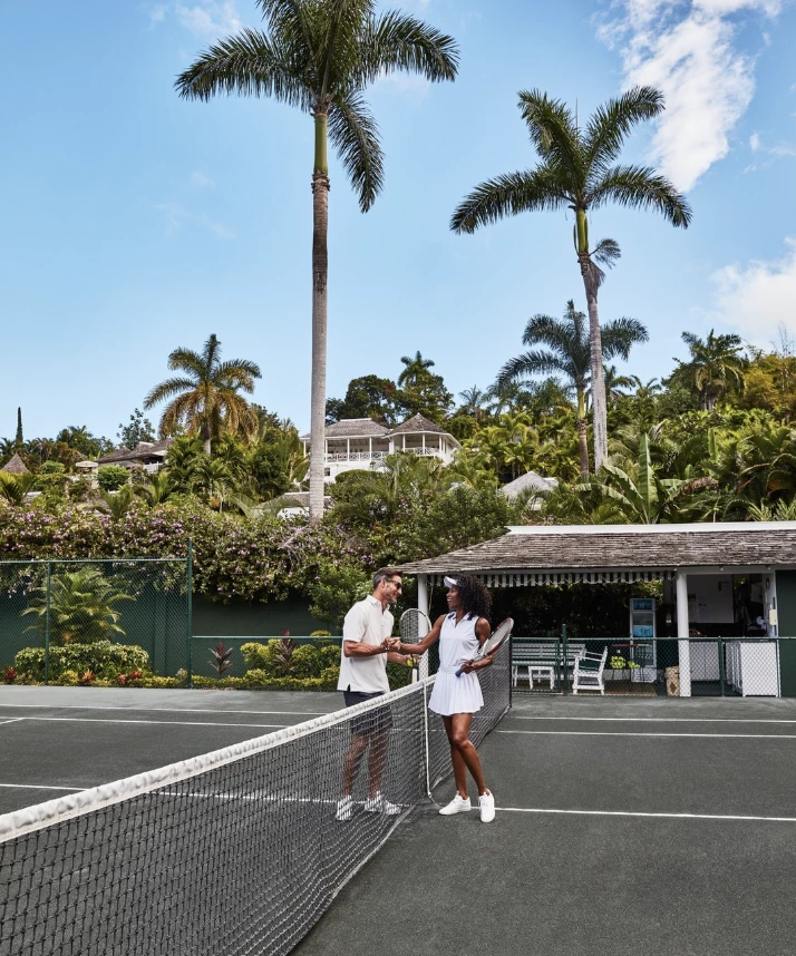 a man and woman shaking hands on a tennis court