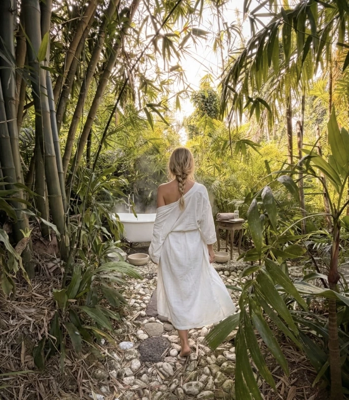 a woman in a white robe walking through a garden