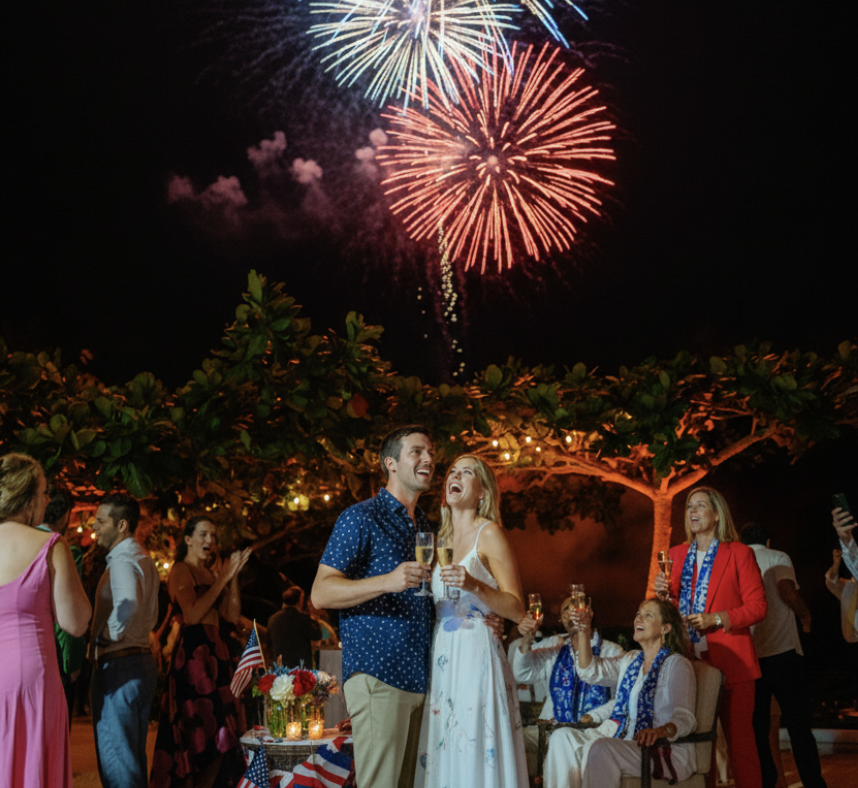 a man and woman standing in front of fireworks