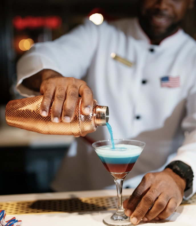 a person pouring a drink into a glass